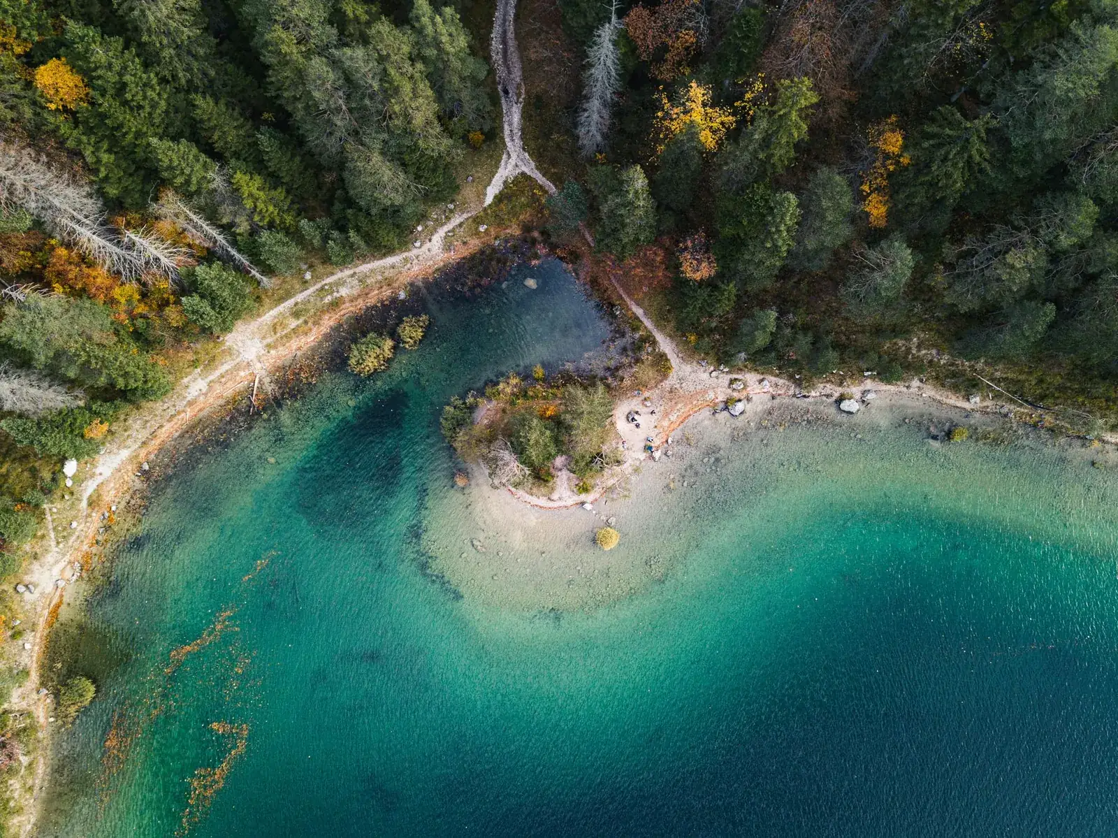 Luftaufnahme eines türkisfarbenen Bergsees mit Wald