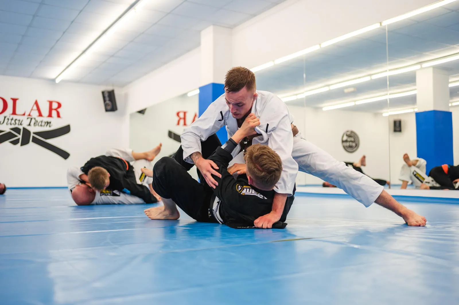 Zwei Kämpfer beim Jiu-Jitsu-Training auf blauer Matte